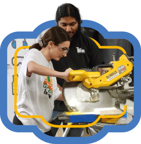 A Houston ToolBank staff member showing a volunteer how to use a saw