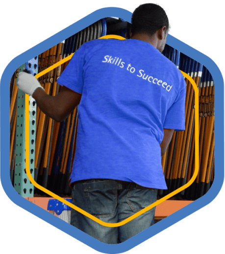 A blue badge showing a Houston ToolBank volunteer wearing a shirt that says, "Skills to Succeed"