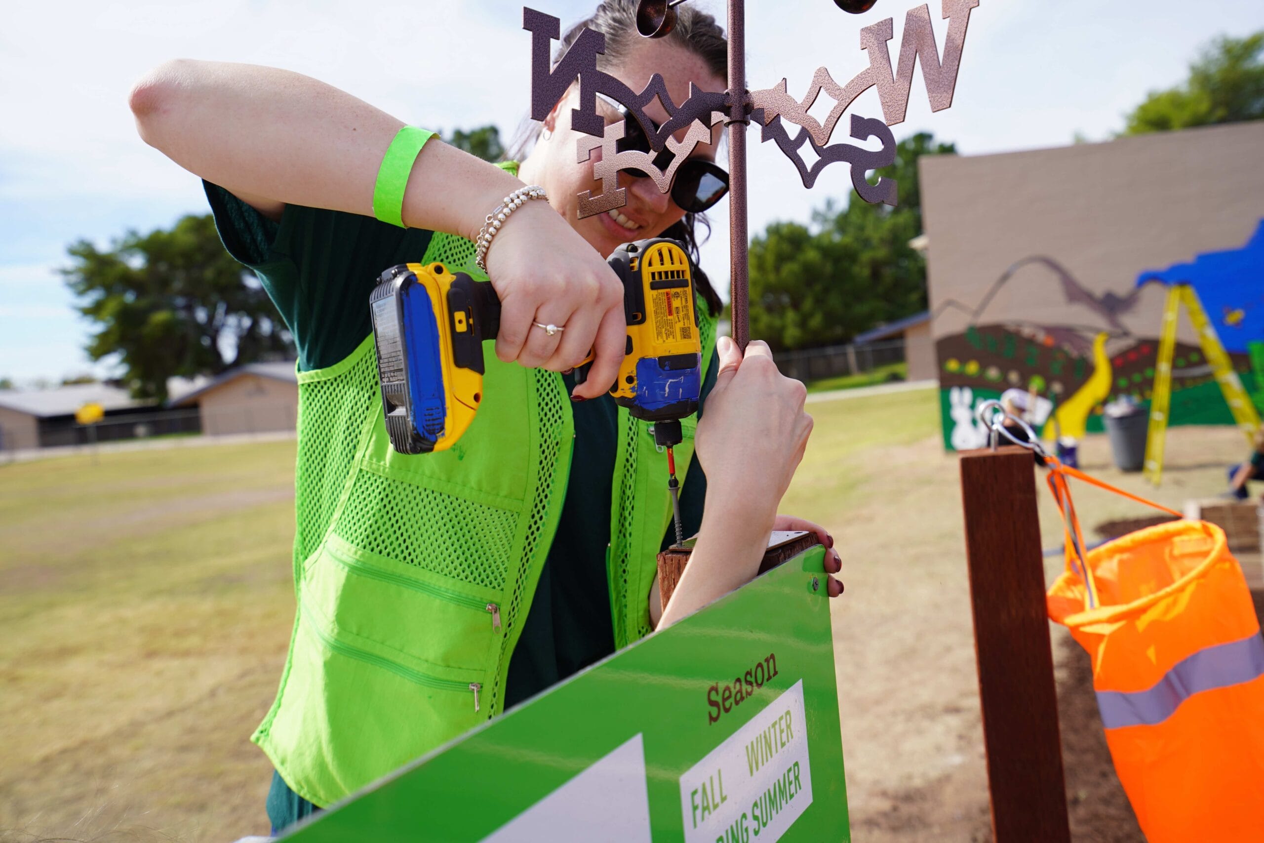 A volunteer in a green vest drilling into a sign