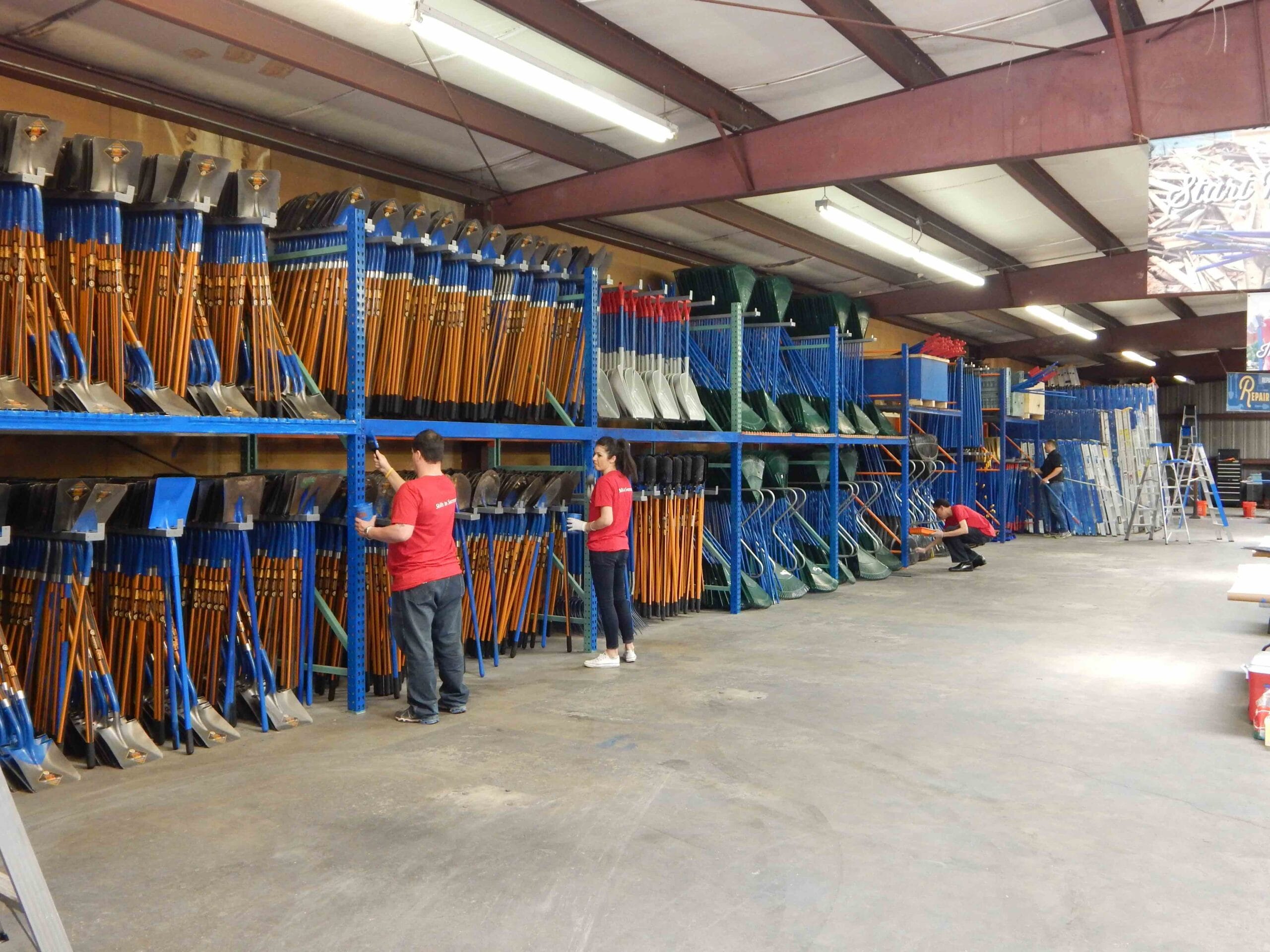 Houston ToolBank volunteers looking over rows of tools neatly stored in the ToolBank's warehouse