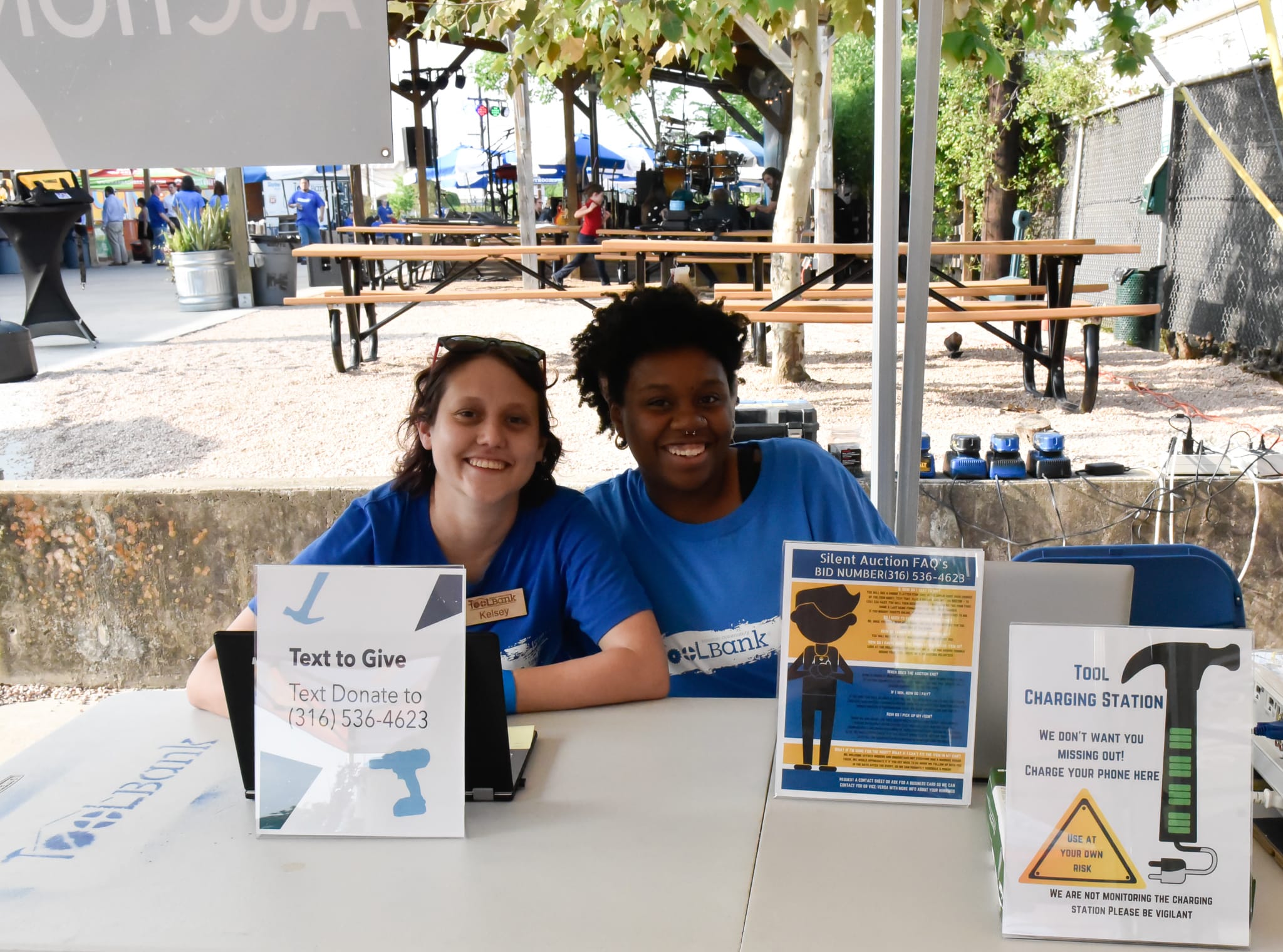 Two Houston ToolBank volunteers sitting at a ToolBank table asking people to sign up