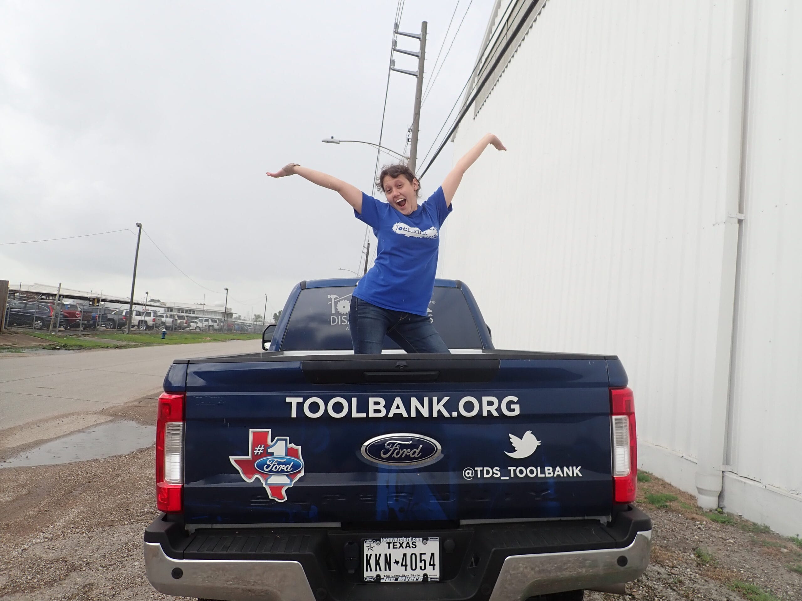 A Houston ToolBank Volunteer throwing her hands up int he back of a pickup truck