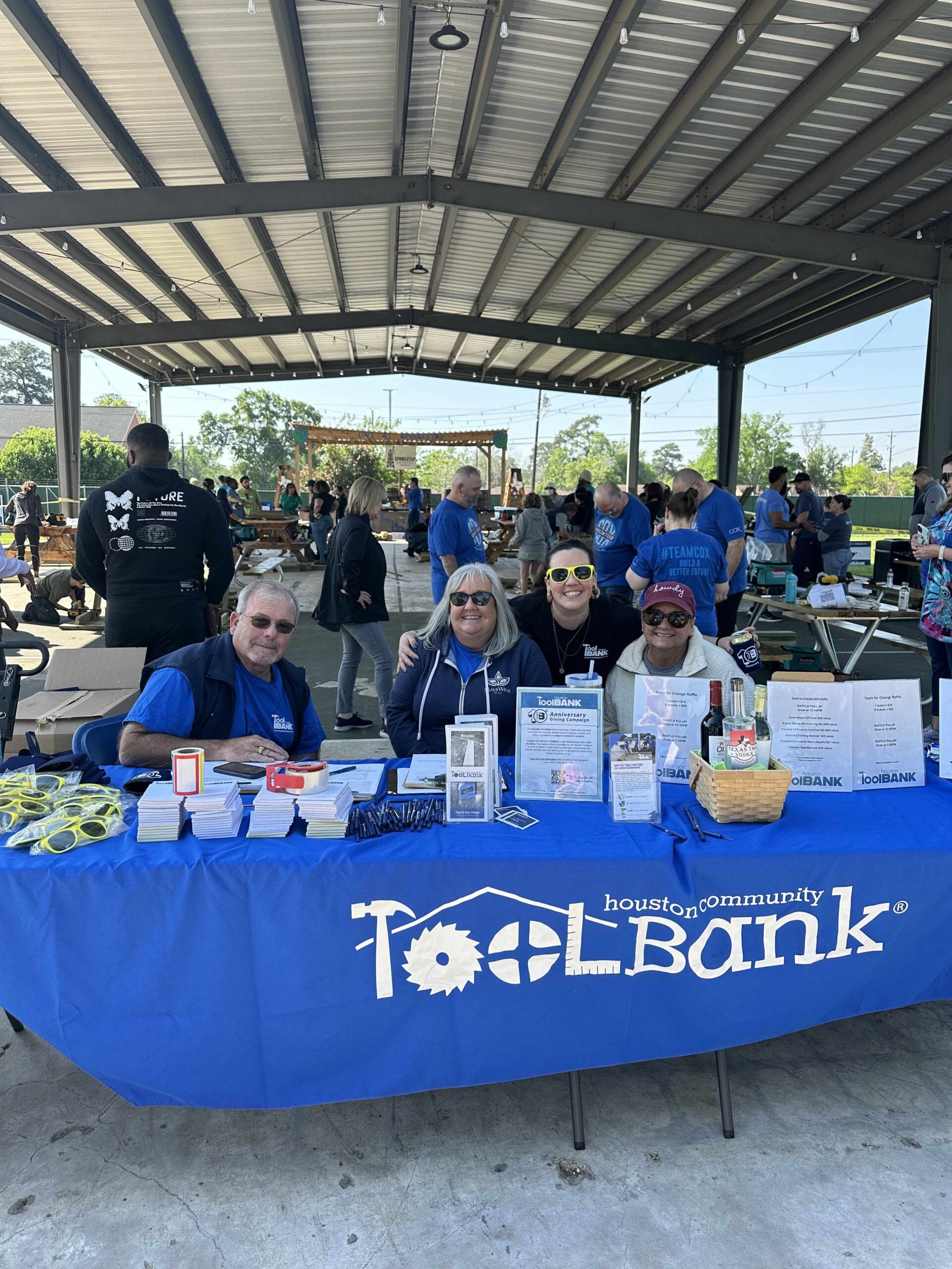 Houston ToolBank volunteers sitting a table handing out ToolBank swag