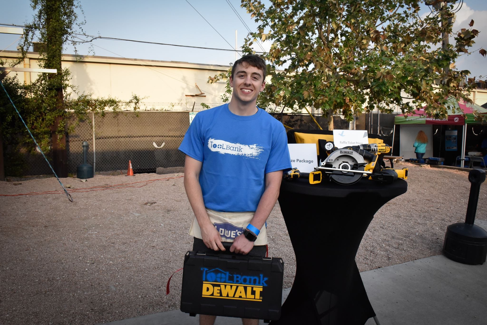 A Houston ToolBank volunteer standing next to DeWalt tools donated to the ToolBank