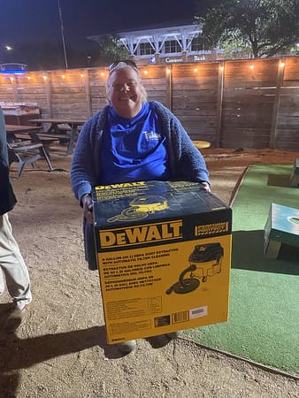 A Houston ToolBank volunteer holding a DeWalt dust vacuum