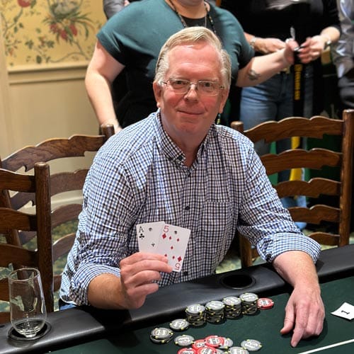 A man holding up cards at a poker table