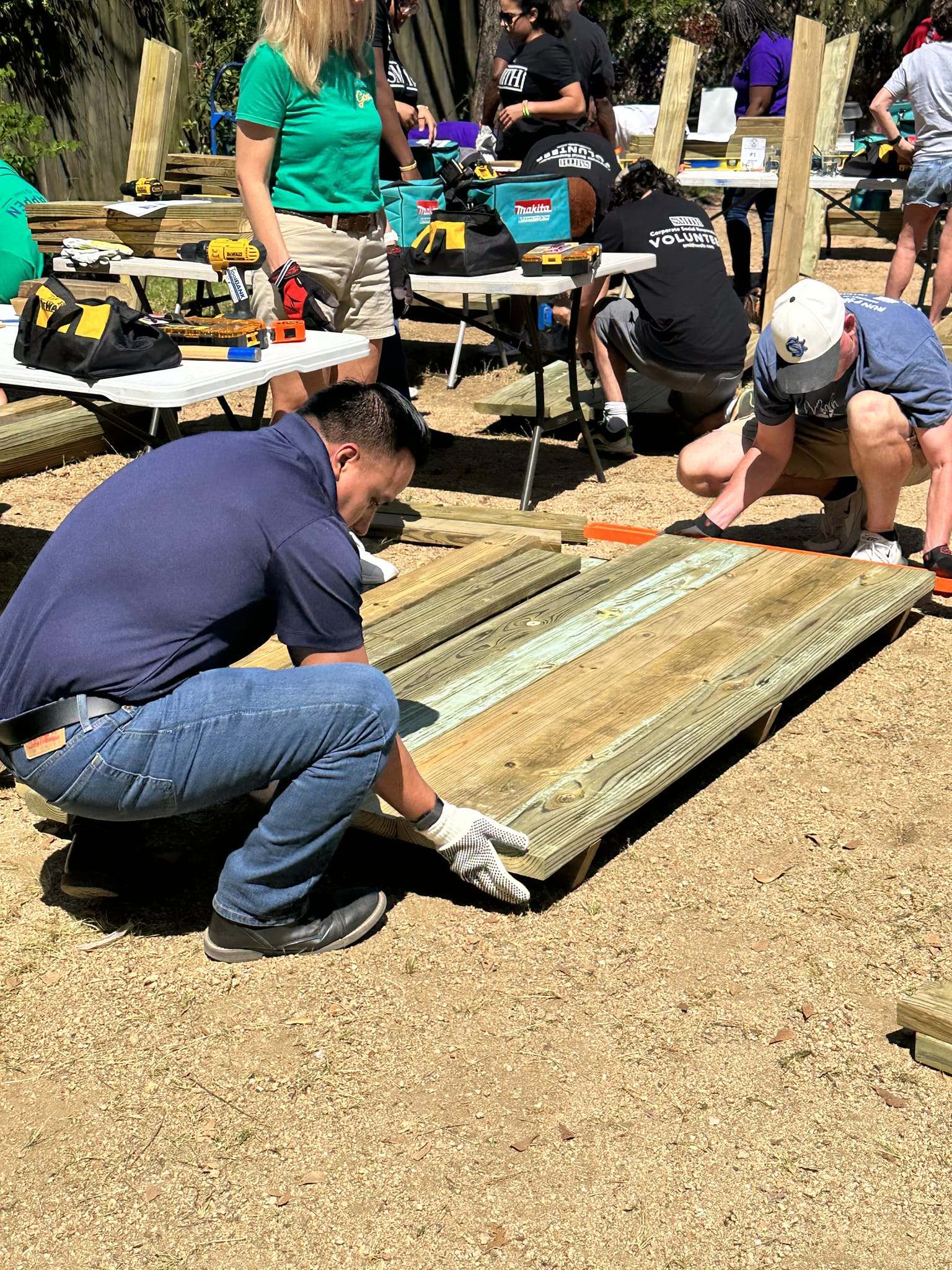 Two volunteers lowering the top of a wooden lunch table to the ground at a Houston ToolBank event