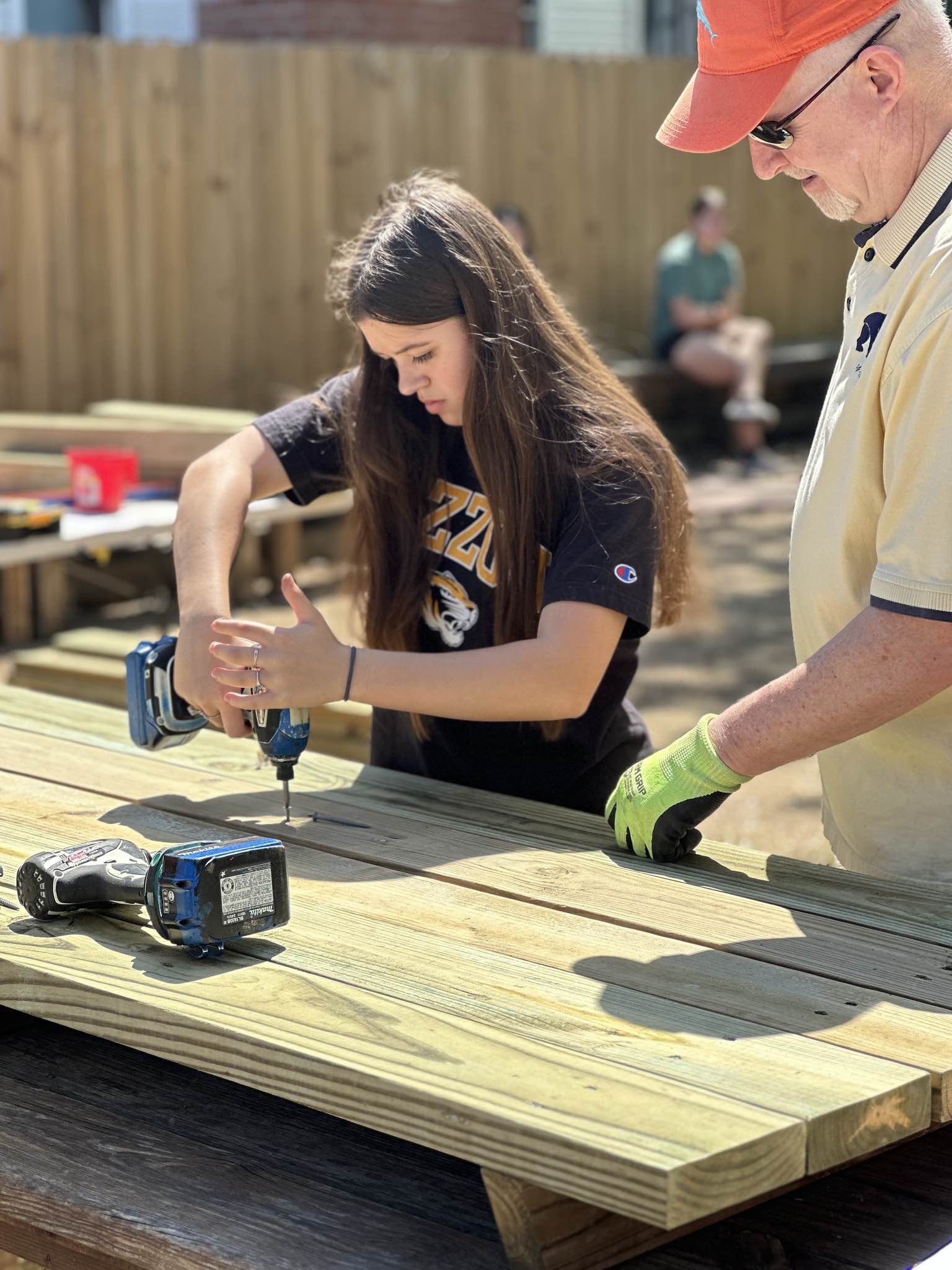 A teenage girl drilling a hole in a table