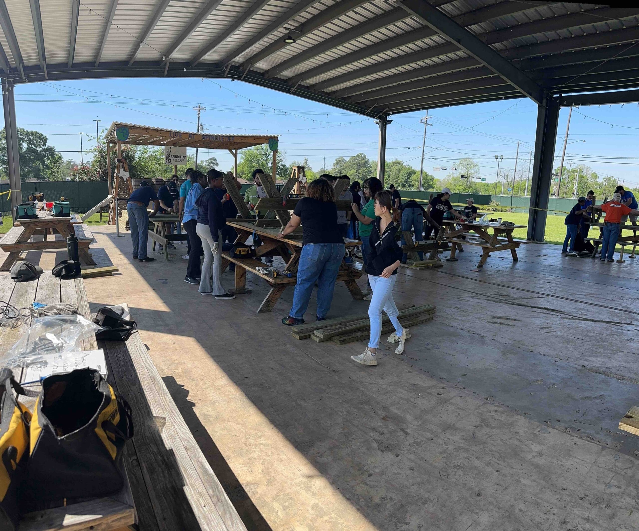 Houston ToolBank volunteers building lunch tables under a school hardtop