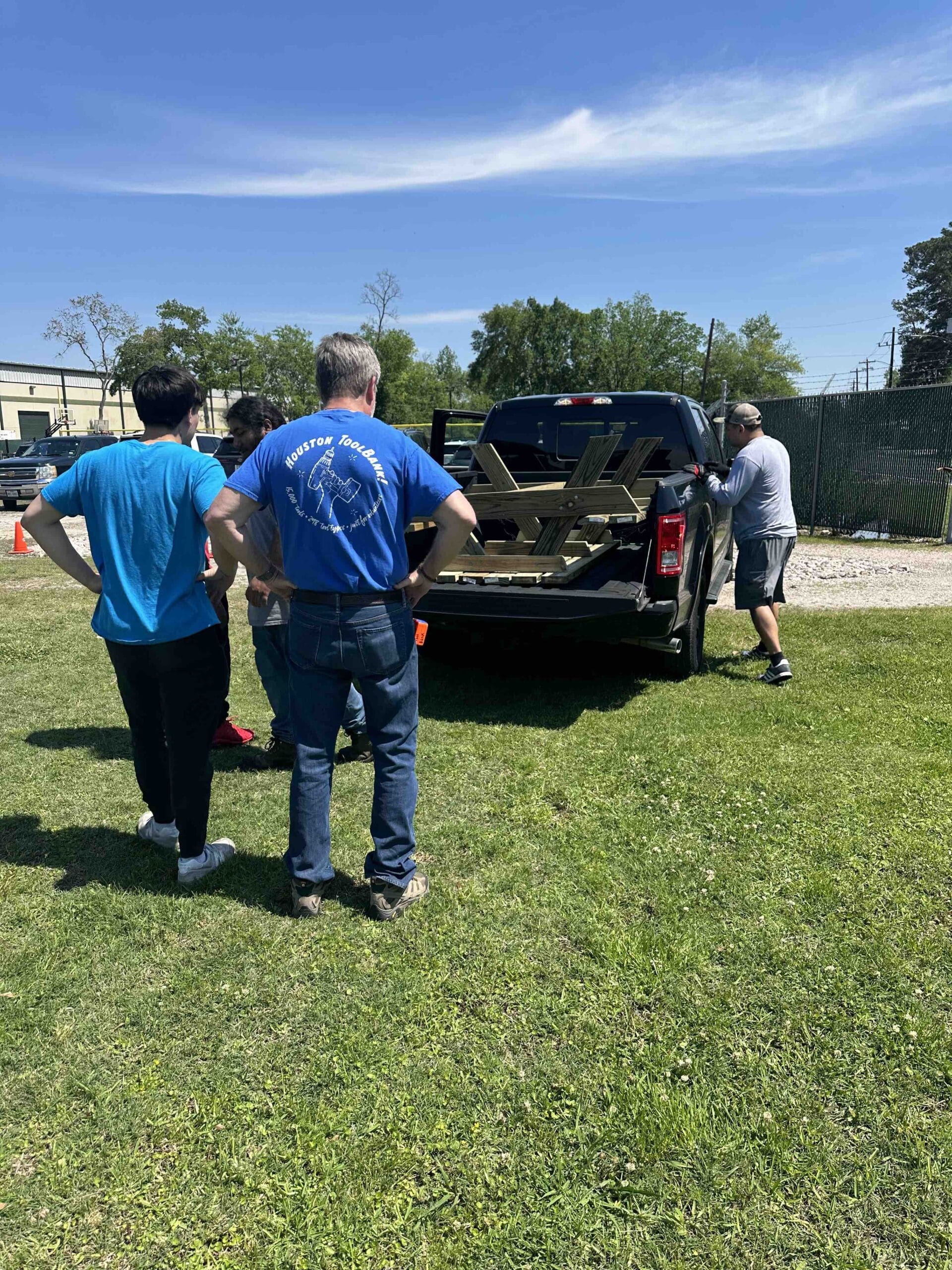 Houston ToolBank volunteers loading at a wooden lunch table into the back of a truck