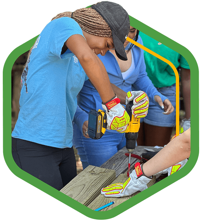 A green badge featuring a young woman drilling down on a wooden plank