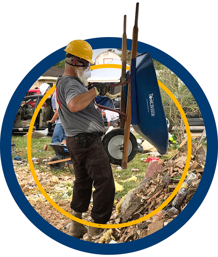 A Houston ToolBank volunteer dumping out his blue wheelbarrow