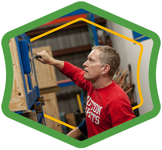 A green badge showing a Houston ToolBank volunteer painting a table blue