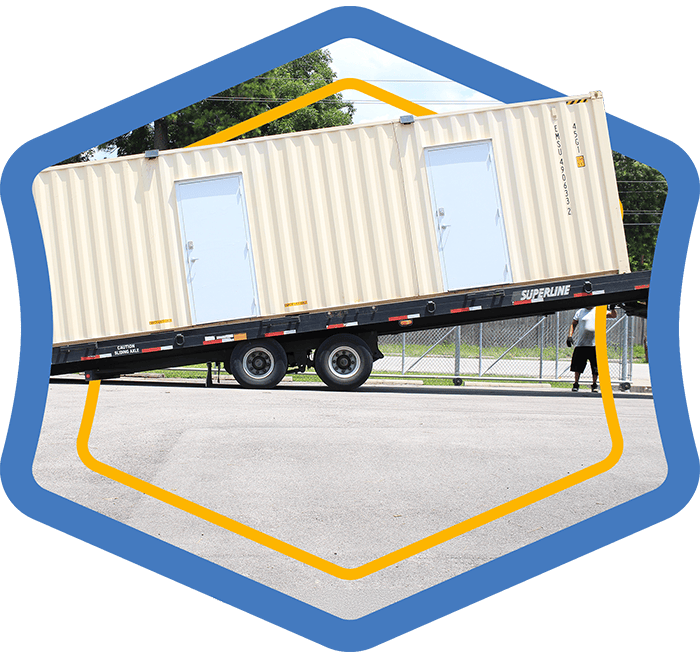 A blue bade showing a modular storage container being loaded on a trailer